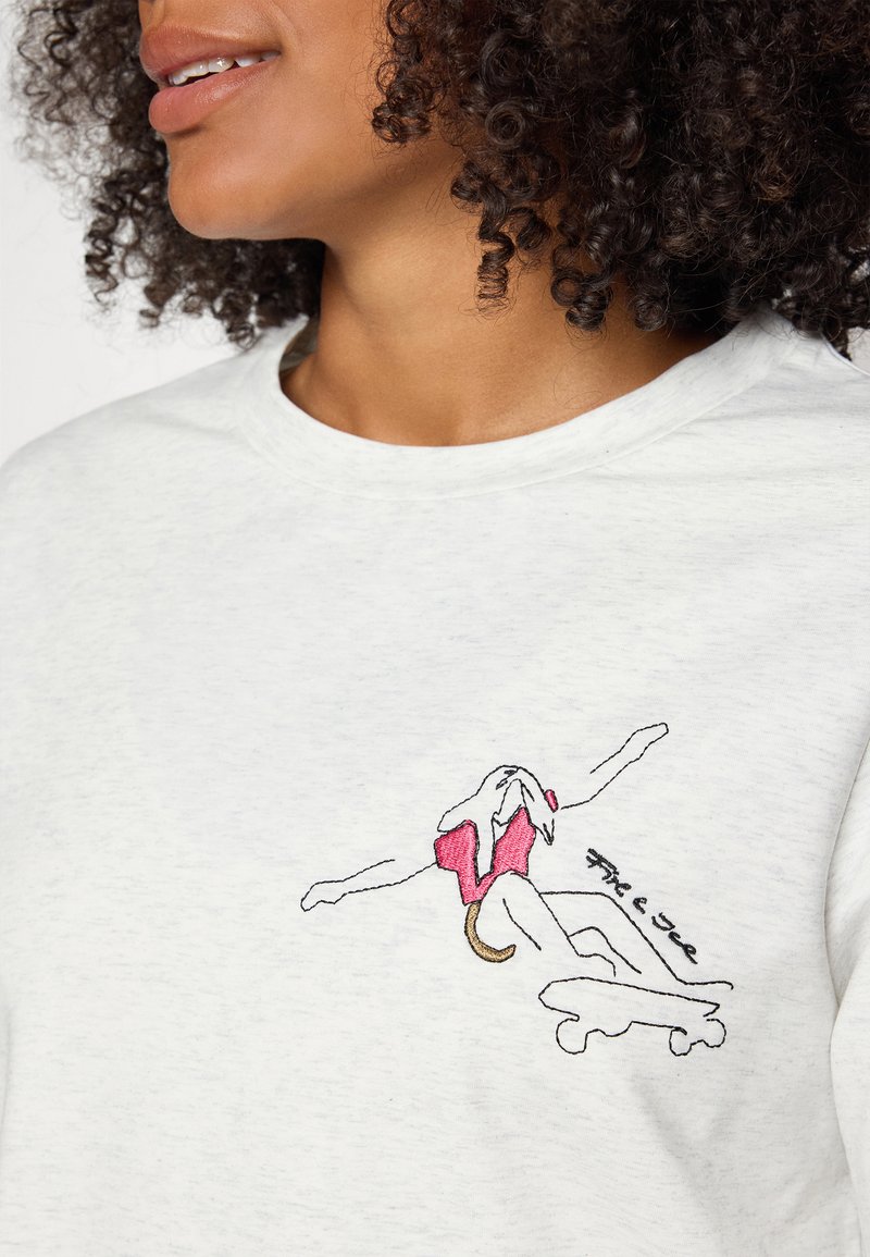 Hellgraues T-Shirt mit Rundhalsausschnitt, das ein bunt besticktes Design einer Figur zeigt, die im rosa Badeanzug Skateboard fährt.