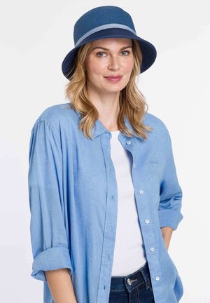 Blue straw bucket hat with a light gray band, paired with a light blue button-up shirt and a white top, displayed on a neutral background.