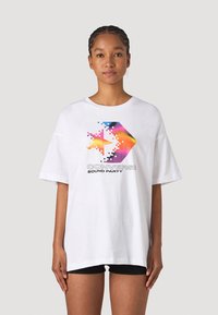 Camiseta blanca oversize con un gráfico de estrella pixelada colorida y el texto "CONVERSE SOUND PARTY", fabricada en algodón. Mangas cortas.