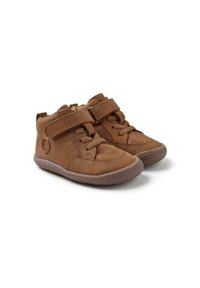 Botas de tobillo de cuero marrón con correas de velcro, detalles de cordones, cuello acolchado y suelas de goma. Presentan un emblema circular en el lateral.