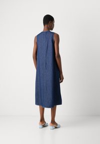 Jeanskjole uten ermer i mørkeblått, med løs passform og kne-lengde design. Har en rett bakside og minimale sømdetaljer.