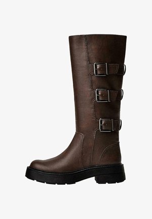 Botte en cuir marron jusqu'au genou avec trois boucles métalliques, surface texturée, bout rond et semelle épaisse pour la stabilité.