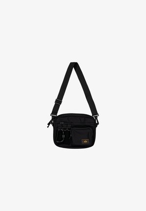 Zwarte nylon schoudertas met verstelbare schouderband, meerdere ritszakken en hardware-accenten. Kenmerkt zich door een logo-patch aan de voorkant en een textuurovervlak.
