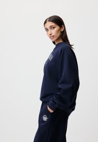 Sweatshirt bleu marine à coupe décontractée, avec un col rond et un détail de logo brodé. Assorti à un pantalon avec un logo similaire.