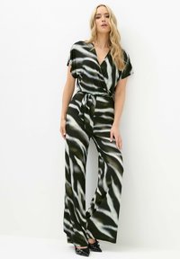 Mono estilo wrap que presenta un audaz patrón de olas en negro, verde y blanco, con piernas amplias y un cinturón a juego que se ata en la cintura.