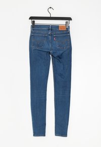 Jean skinny en denim, avec deux poches arrière, une étiquette en cuir sur la taille et des coutures contrastées.