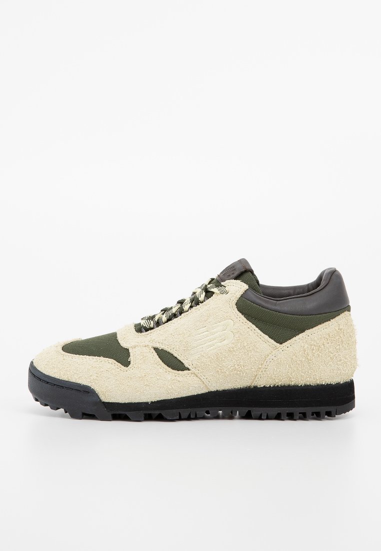 Baskets beiges texturées avec un revêtement en nylon vert olive, semelle noire et lacets à motifs. Présente un logo discret sur le côté.