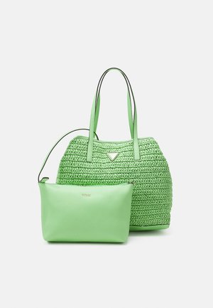Deux sacs à main Guess verts, un sac fourre-tout tissé avec double anses et une pochette zippée lisse, présentés sur un fond uni.