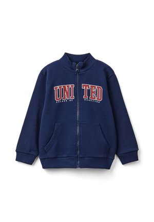 Veste zippée bleu marine en matériau doux, avec un col haut, deux poches avant, et l'impression "UNITED" en rouge et blanc.