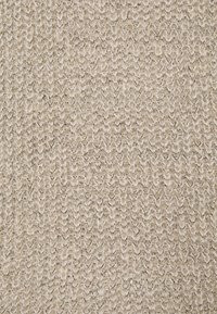 Beżowa dzianina z grubym, pętelkowym wzorem, tworząca teksturowaną, ciepłą powierzchnię tkaniny.