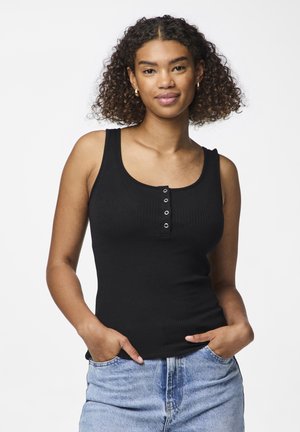 Top de tirantes negro con cuello redondo y una tapeta de cinco botones. Combinado con unos pantalones vaqueros de tiro alto en un tono azul claro.