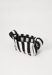 Borsa a righe bianche e nere realizzata in materiale a costine con una consistenza morbida, dotata di manici e nome del marchio ricamato.