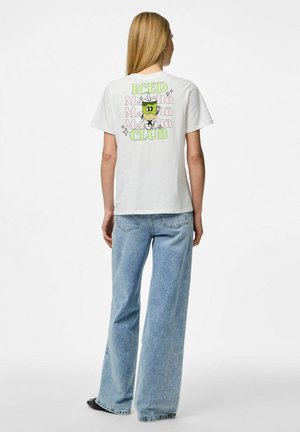 T-shirt blanc à manches courtes présentant un graphique multicolore d'une boisson glacée avec le texte "ICED Matcha Club" au dos. Porté avec un jean bleu clair.