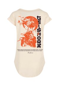 Cream-colored t-shirt featuring an orange graphic of a woman with a parasol and floral accents on the back, with bold text and a soft texture.