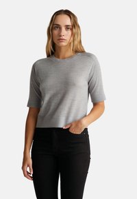 Szary krótki top z dzianiny z okrągłym dekoltem, dopasowanym krojem i subtelną teksturą, w komplecie z czarnymi spodniami.