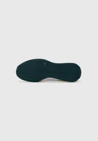 Semelle de chaussure en caoutchouc vert foncé avec un motif en chevrons, présentant un bord lisse et une légère courbure au talon pour une forme ergonomique.