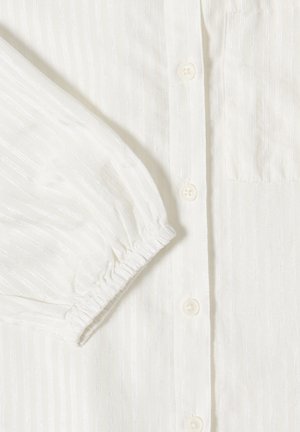 Camicia bianca a maniche lunghe con righe verticali in rilievo, polsino elastico, abbottonatura e taschino sul petto in tessuto liscio.