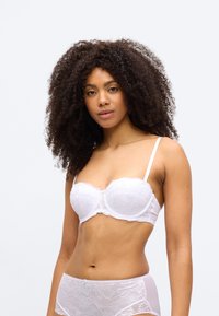 Λευκό δαντελένιο σουτιέν με μπροστινή στήριξη, διαθέτοντας ρυθμιζόμενους ιμάντες και ανθικό σχέδιο. Ομαλή υφή με κυματιστές λεπτομέρειες κατά μήκος των άκρων.