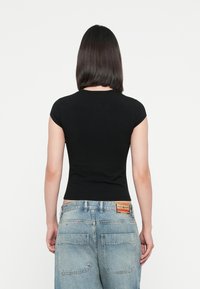 Black fitted t-shirt with short sleeves, smooth texture, round neckline, and a flattering silhouette, paired with light blue denim jeans.