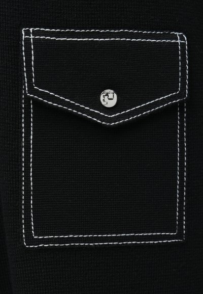 Fekete anyag texturált felülettel és egy foltzsebbel. A zseben fehér varrás és egy kerek ezüstgomb található.