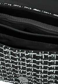 Borsa a mano intrecciata in bianco e nero con esterno testurizzato, chiusura magnetica e tasca interna con zip, caratterizzata da un design elegante e strutturato.