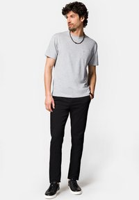 Szara bawełniana koszulka z okrągłym dekoltem i krótkimi rękawami, zestawiona z czarnymi dopasowanymi spodniami i czarnymi trampkami z białą podeszwą.