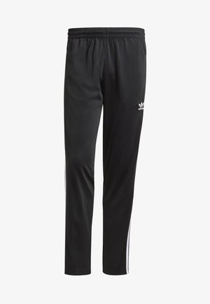Černé tepláky Adidas s bílými bočními pruhy, elastickým pasem a malým logem trefoil na levé horní stehně.