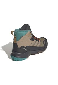 Hiking shoe in brown, black, and teal with a textured upper, orange laces, and gripped sole. Features a pull tab at the heel and logo accents.