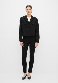 Czarna krótka kurtka z zapięciem na guziki, z dwiema przednimi kieszeniami i naramiennikami. Połączona z czarnymi spodniami slim-fit i czarnymi balerinami.