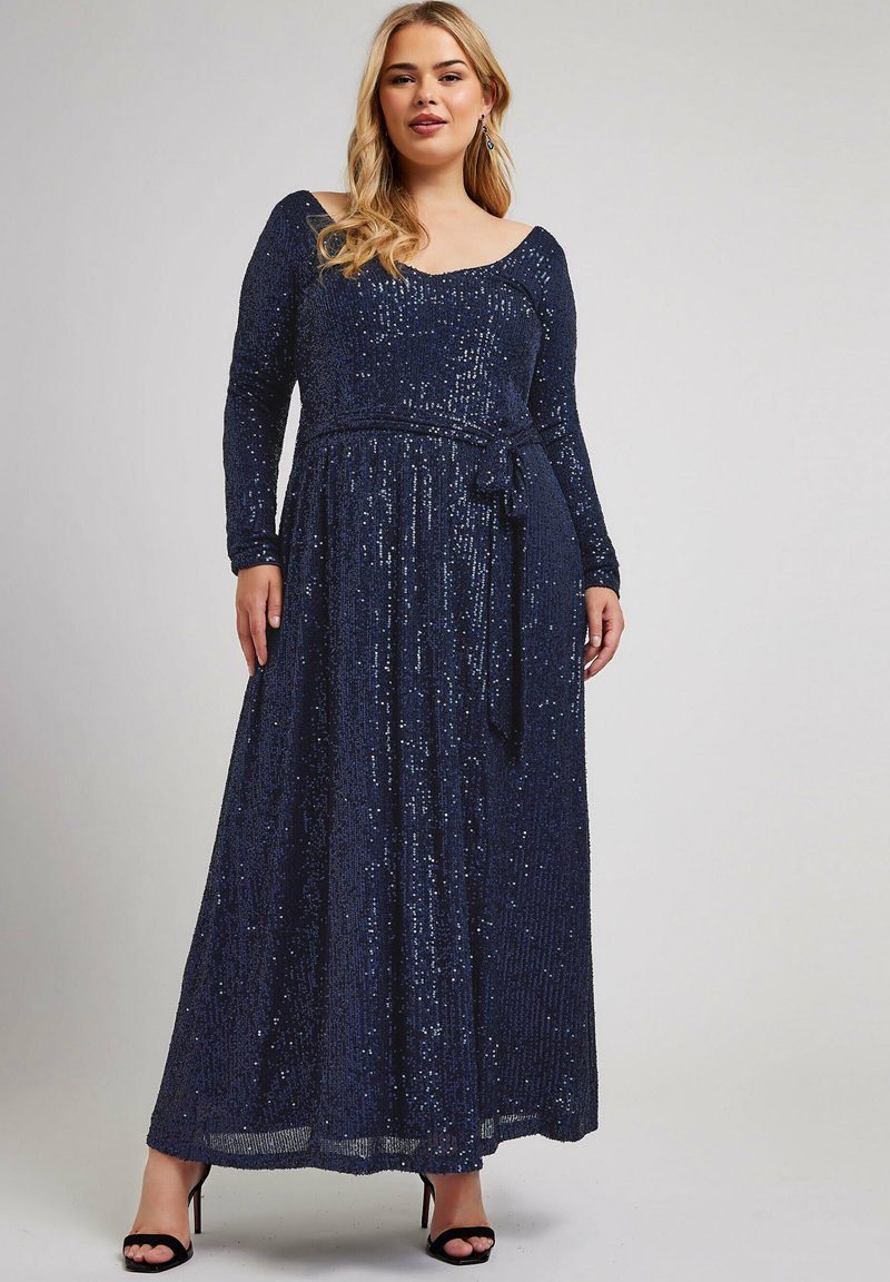 Abito maxi in paillettes blu navy con maniche lunghe, scollo a barca e vita legata. Presenta una gonna fluente e una finitura testurizzata.