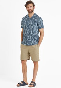 Short-sleeve button-up shirt with a blue leaf pattern, paired with khaki shorts, and navy sandals.
