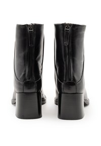 Stivali alla caviglia in pelle nera con punta arrotondata, zip posteriore e tacco quadrato spesso. Texture liscia con una finitura lucida.