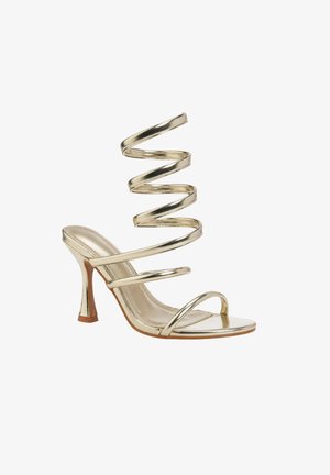 Sandale à talons hauts dorée avec une bride en spirale qui s'enroule autour de la jambe, bout ouvert et trois fines brides sur le pied.