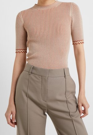 Haut à col montant et manches courtes beige, avec des côtes verticales et des rayures rouille contrastantes ; détails à bord festonné sur les manches.