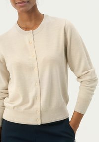 Beige kardigan pehmest kudumist, ümmarguse kaeluse, nööpidega esiosa ning soonikustega varruka- ja alumise äärtega.