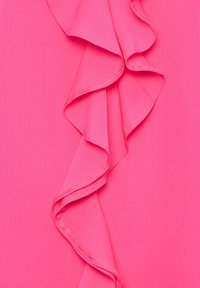 Tissu rose vif avec un détail de volants verticaux présentant des ondulations douces et fluides et des bords cousus en vue rapprochée.