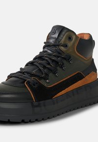 Černé a olivově zelené vysoké tenisky z kůže a semiše, s texturovanými povrchy a oranžovým zdobením stehy na silné podrážce.