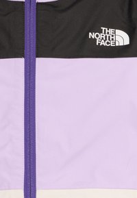 Világoslila dzseki fekete felső résszel, elöl cipzárral és fehér "The North Face" logóval. Simább textil anyag.