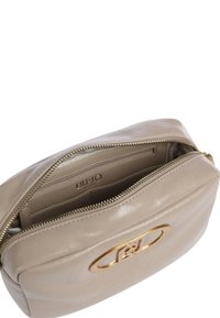 Borsa a tracolla in pelle beige con chiusura a zip, caratterizzata da un dettaglio del logo in tono oro sul davanti e una tasca interna foderata.