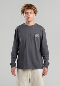 Long-sleeve, gray cotton t-shirt with a small white graphic on the left chest; crew neck, relaxed fit, and double-stitched cuffs.