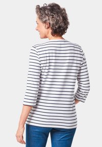 Gestreepte dames top in wit en marineblauw, met driekwart mouwen en een ronde halslijn, gemaakt van zachte, lichte stof.