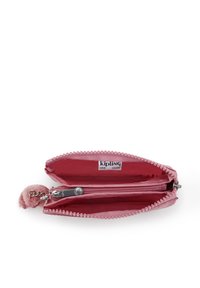 Kipling roze ritstas met een textuur op de buitenkant, een pompon ritsen trekken, en interieurcompartimenten voor organisatie en opberging.