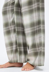 Καρό πιτζάμα παντελόνια σε πράσινο, γκρι και λευκό με ροζ λεπτομέρειες, κατασκευασμένα από μαλακό, βουρτσισμένο ύφασμα· φαρδιά πόδια και ορατή ελαστική μέση.