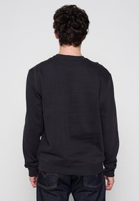 Felpa nera in cotone con maniche lunghe e scollo rotondo, caratterizzata da un design posteriore semplice e senza decorazioni.