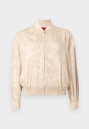 Ανοιχτό μπεζ bomber μπουφάν με διακριτικό μοτίβο tie-dye, κλείσιμο με φερμουάρ, ελαστικές μανσέτες και ζώνη στη μέση, παρουσιάζεται σε απλό φόντο.