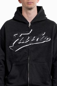 Black zip-up hoodie featuring a large, distressed white graphic on the chest, front pockets, and a drawstring hood. Soft fabric texture.