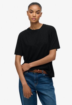 Sort kortærmet T-shirt lavet af blødt stof, med en afslappet pasform og rund halsudskæring, parret med blå denimjeans og et vævet brunt bælte.