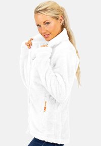 Witte fleece jas met een hoge kraag, rits aan de voorkant en zijzakken. Heeft een zachte textuur en oranje ritsaccenten.