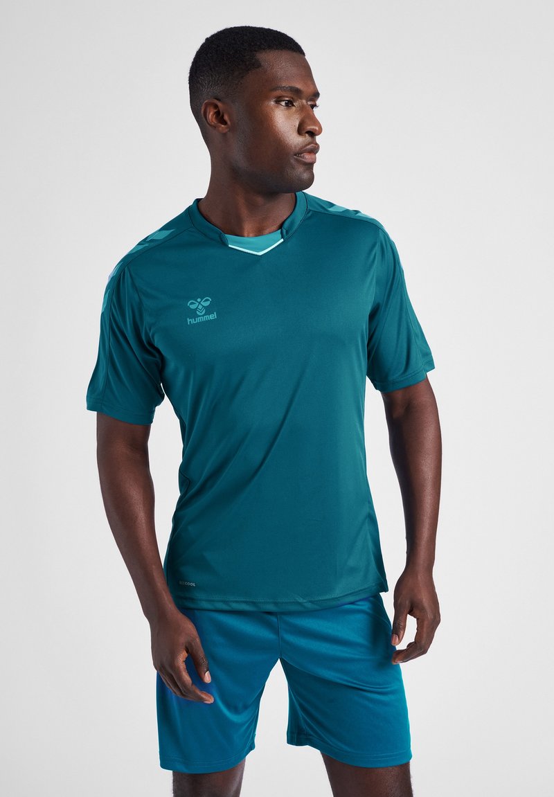 Teal atletisk skjorte med korte ærmer og rund krave, der har lys blå detaljer og et logo. Sammen med matchende teal shorts.