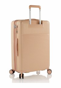 Valigia rigida di colore pesca chiaro con scanalature orizzontali, manico retrattile argentato e quattro ruote nere. Scomparto con cerniera nella parte anteriore.